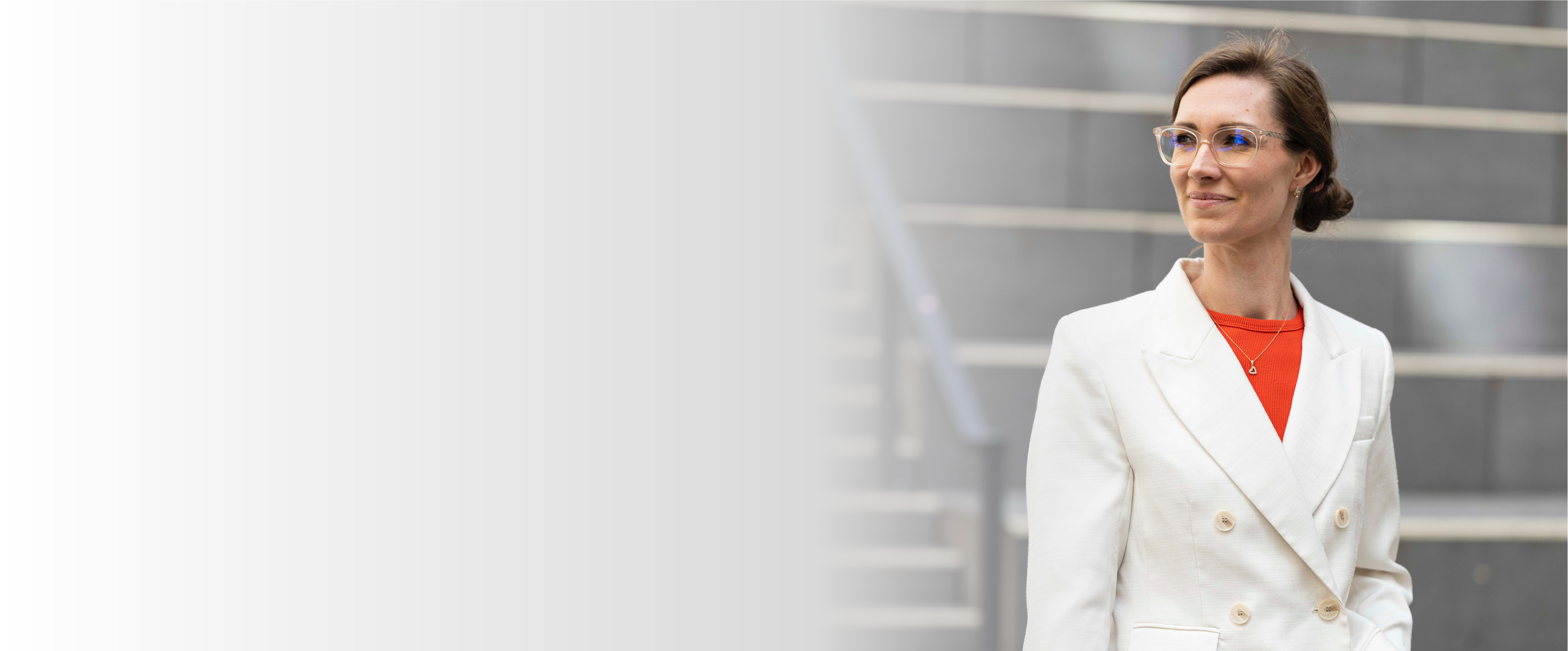 Projektmanagerin Janine Frank trägt einen creme-farbenen Blazer und ein rotes Shirt. Sie schaut souverän nach links.